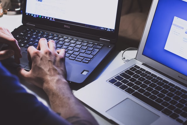 Person browsing two laptops