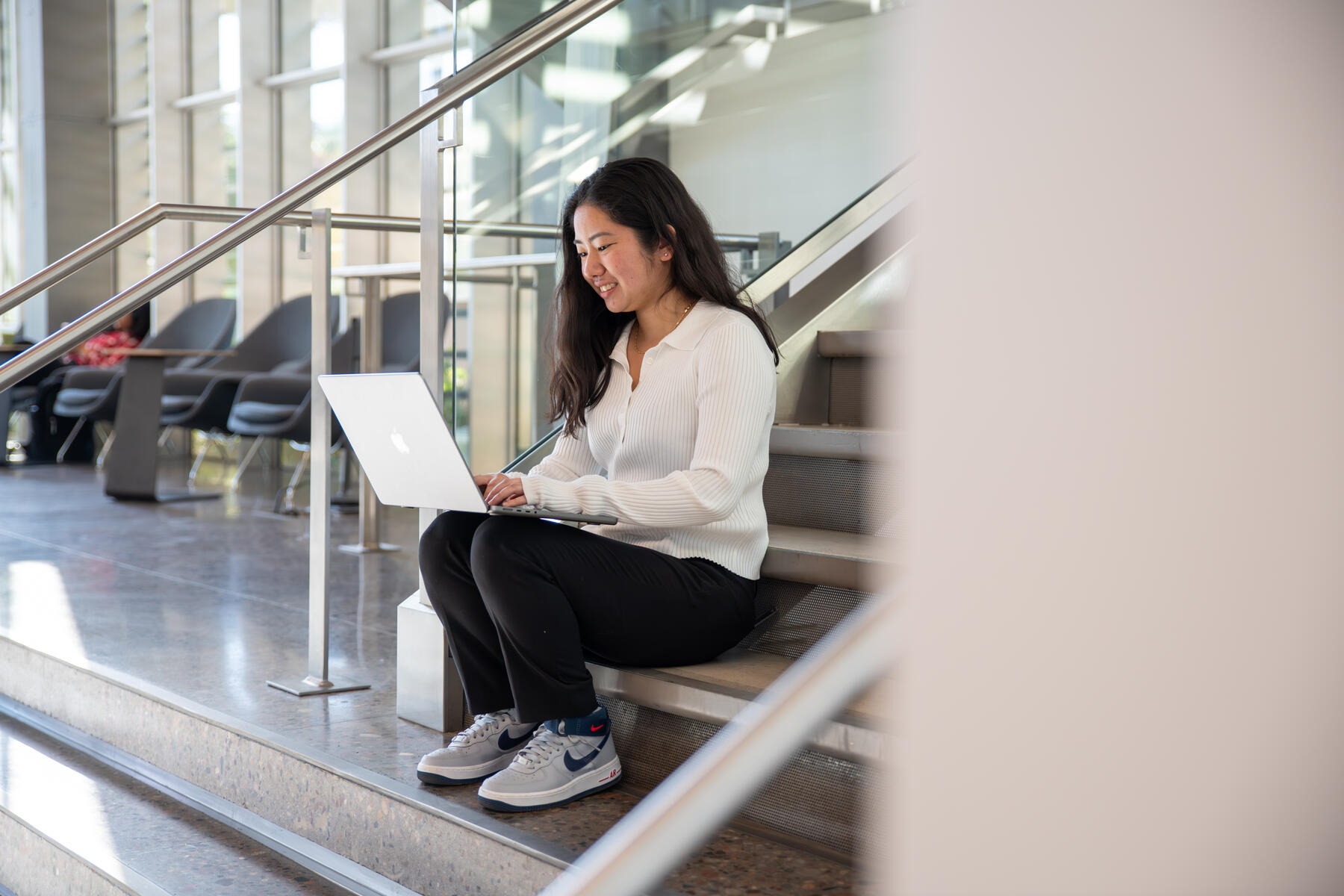 Woman sitting on stairs with her laptop 