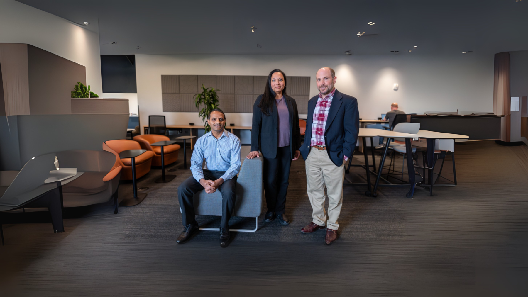 One man sitting and two people, woman and a man, standing
